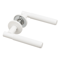 Luxe mat witte Berzo diamond-cut deurklink met geveerd mechanisme en rond rozet voor elegante binnendeuren