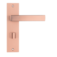 Mat koperen Nola deurklink op 180 × 45 mm kort schild met geïntegreerd WC-slot hartafstand 63 mm voor moderne badkamerdeuren